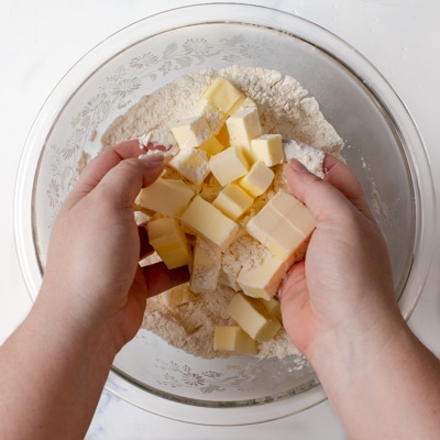 Cold cubed butter being tossed in flour