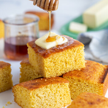 Squares of cornbread topped with butter and honey