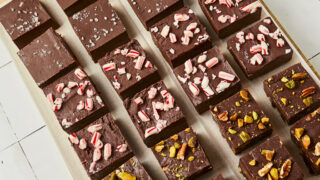 Different flavors of chocolate fudge squares lined up on parchment paper