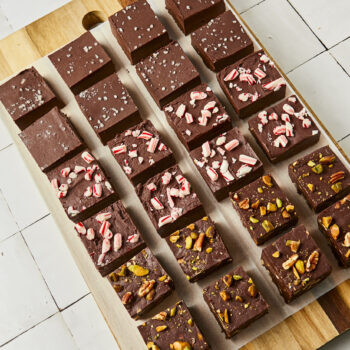 Different flavors of chocolate fudge squares lined up on parchment paper