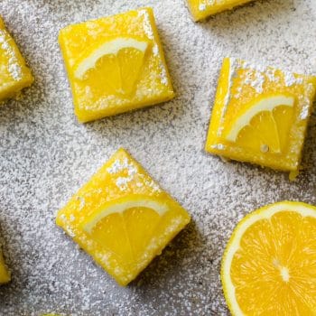 Lemon Bar squares decorated with a lemon slice and sprinkled with powdered sugar