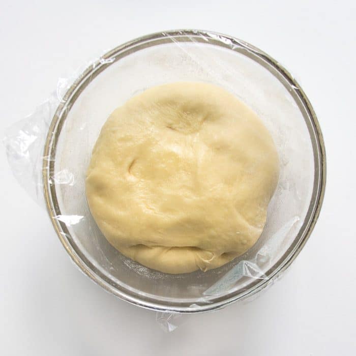 Dough ball in bowl with plastic wrap