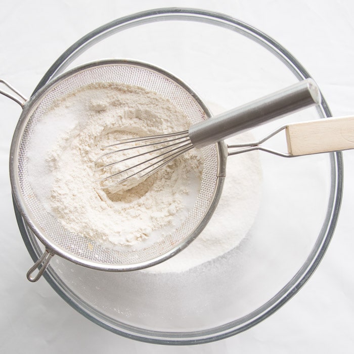 Dry ingredients being sifted through a mesh strainer