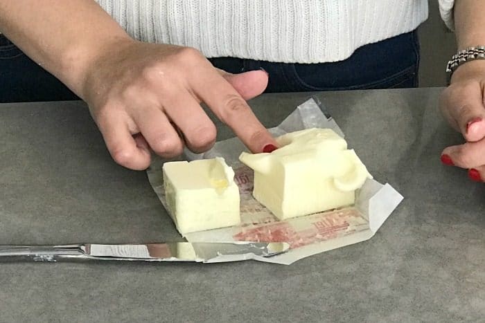 Softened butter that is being pushed on my a finger to show that is it soft