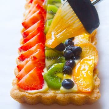 Fruit tart being glazed with fruit glaze