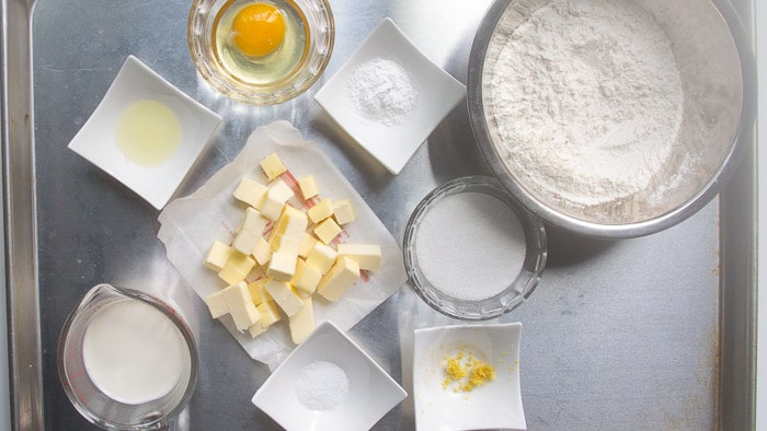 Learn the process of how to make lemon scones that are soft, fluffy, and moist! These lemon scones are tender and flavorful and topped with a tangy lemon glaze! Ingredients measured out for lemon scones