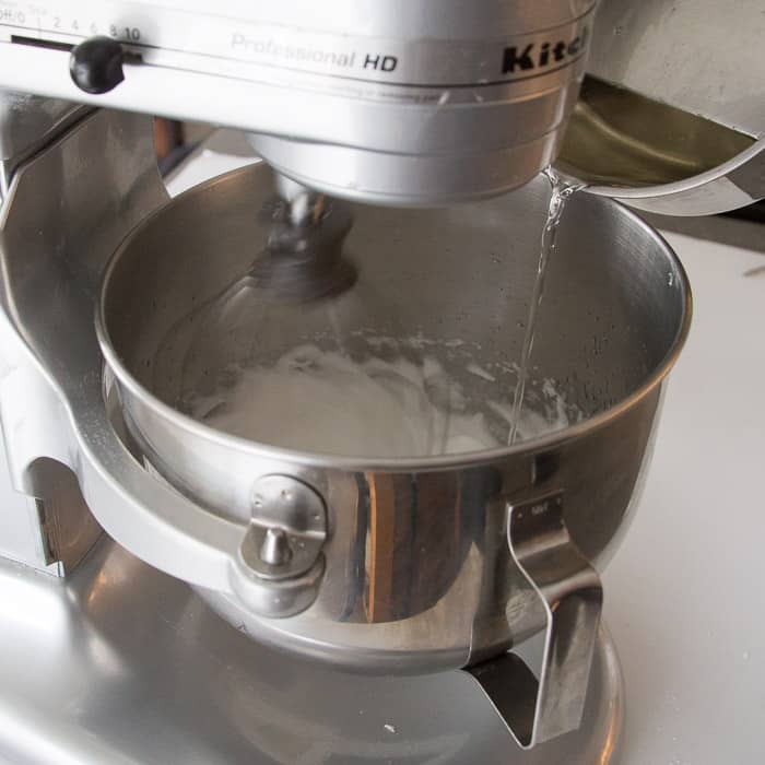 Sugar syrup being poured into whipped egg whites to make Italian Meringue