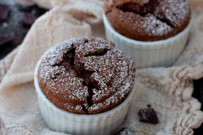 Rich chocolate souffles dusted with powdered sugar with crackly tops