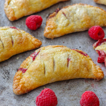 Golden turnovers in a half moon shape filled with raspberry jam on a tray