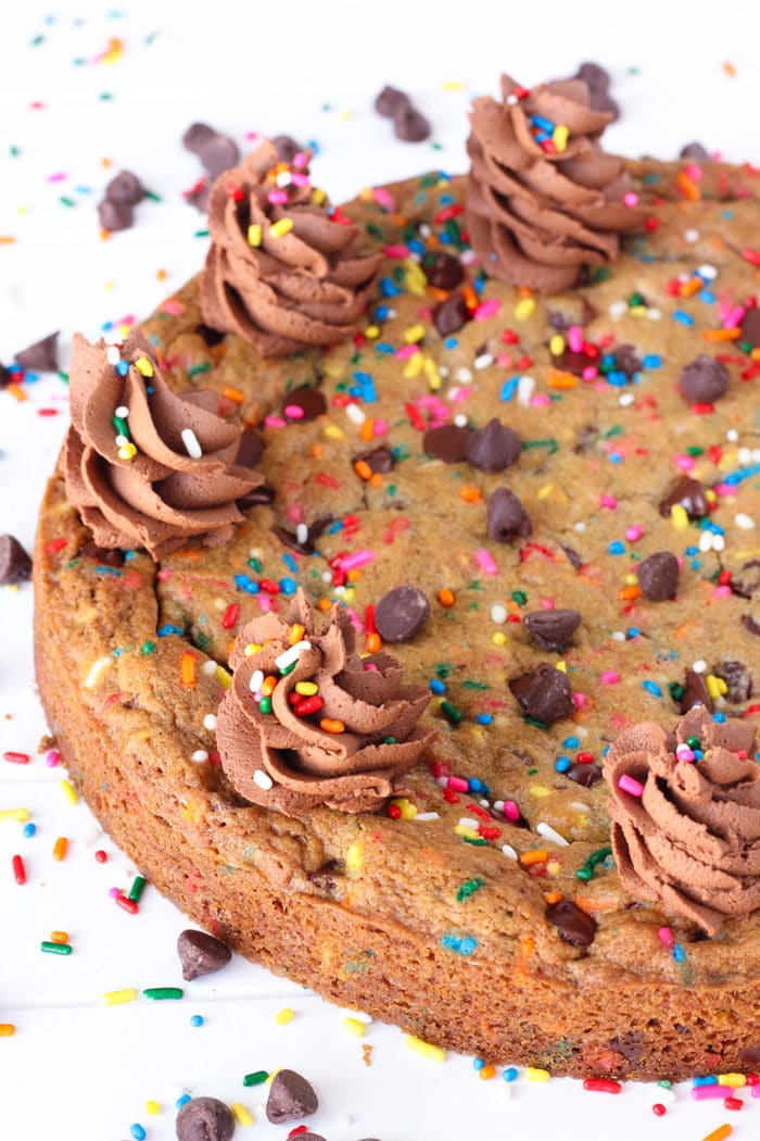 Chocolate Chip Cookie Cake with swirls of frosting on top with colorful sprinkles