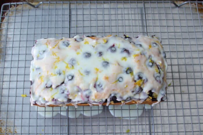 Blueberry bread on a cooling rack after being glazed with a lemon glaze