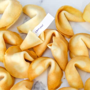 Tray of fortune cookies. One of the cookies is broken open and there is a fortune coming out of it that says "I love you"