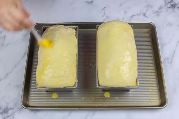 Brushing egg wash on the sandwich loaves