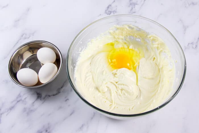 Eggs being added to cheesecake filling