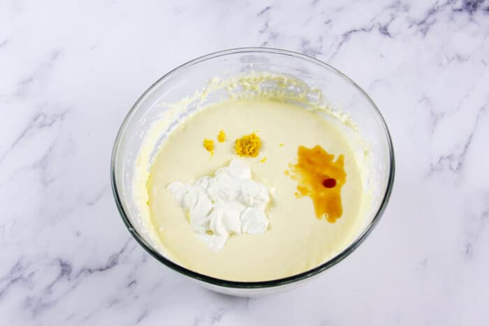 Sour cream, lemon zest, and vanilla being added to cheesecake filling