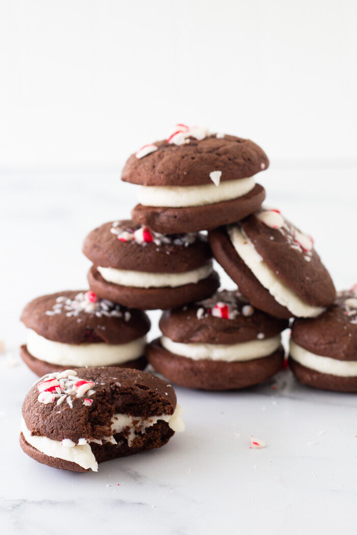 Tower of chocolate peppermint whoopie pies sitting on a marble platter. One cookie in front has a bit taken out of it