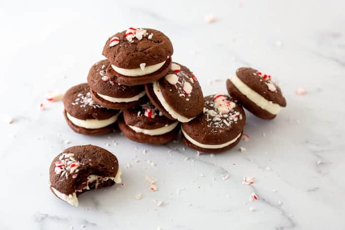 Chocolate peppermint whoopie pies all piled up sitting on a marble platter. One cookie in front has a bit taken out of it