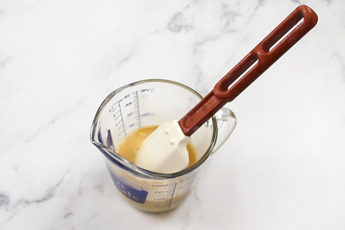 The wet ingredients in a liquid measuring cup after being stirred together. 