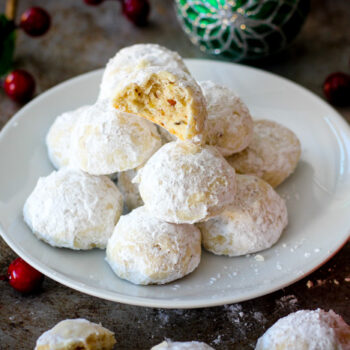 Stack of pecan snowballs. The top one has a bite taken out of it exposing the center