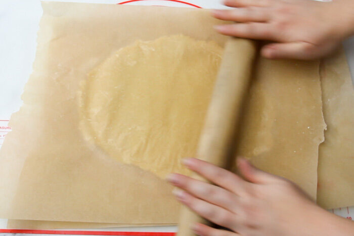 Rolling out sugar cookie dough in between two pieces of parchment paper