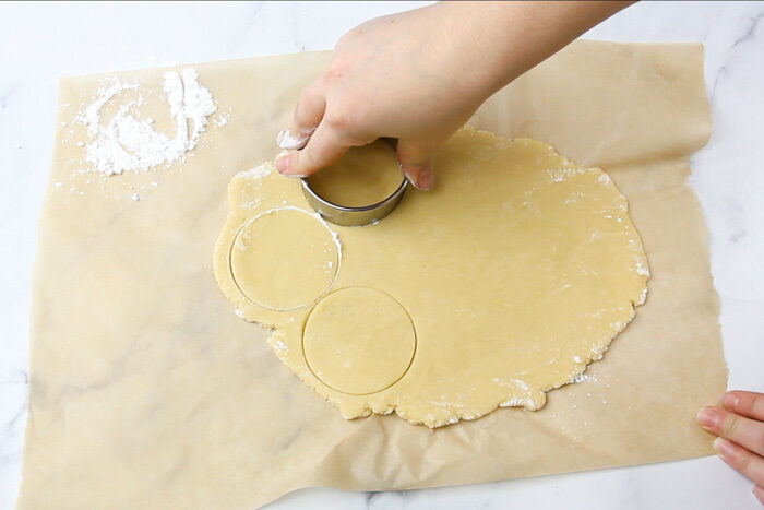 Cooke dough rolled out and a being cut into circles with a round cookie cutter