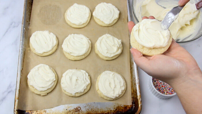 Frosting a baked sugar cookie with simple buttercream frosting