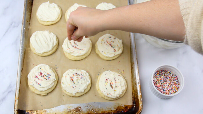Adding sprinkles on top of frosted sour cream sugar cookies