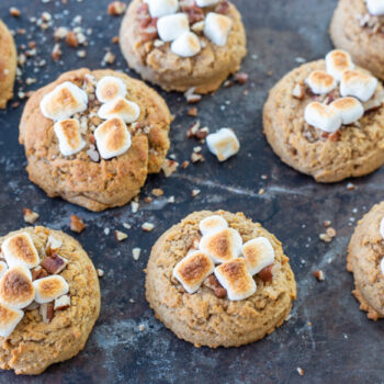 Sweet potato cookies topped with pecans and toasted marshmallows lined up on a baking sheet