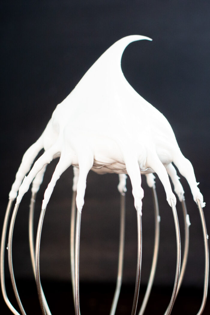Stiff meringue on a whisk holding its peak
