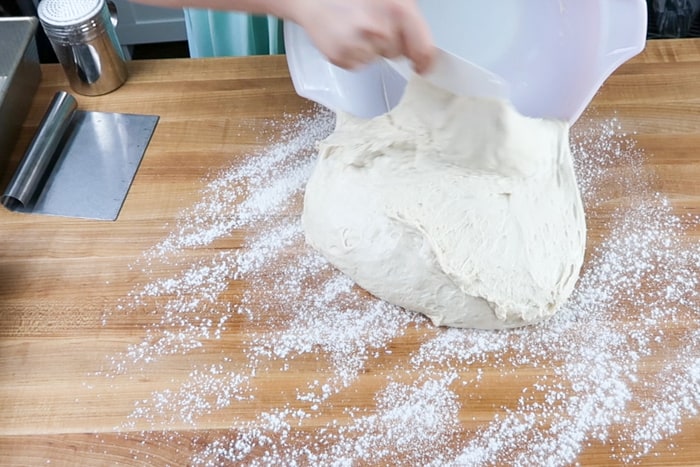 Dough being poured out onto a countertop to knead