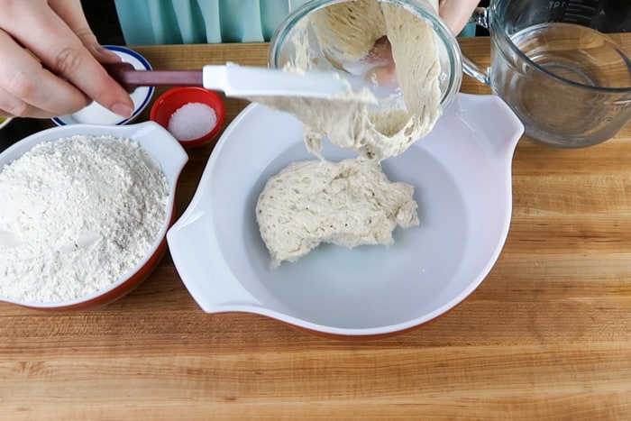 Sourdough starter being added to a bowl of warm water