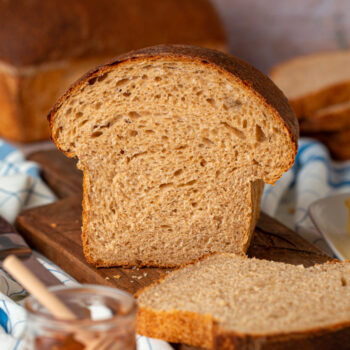 Loaf of honey wheat sourdough sandwich bread that has been cut so you can see the inside