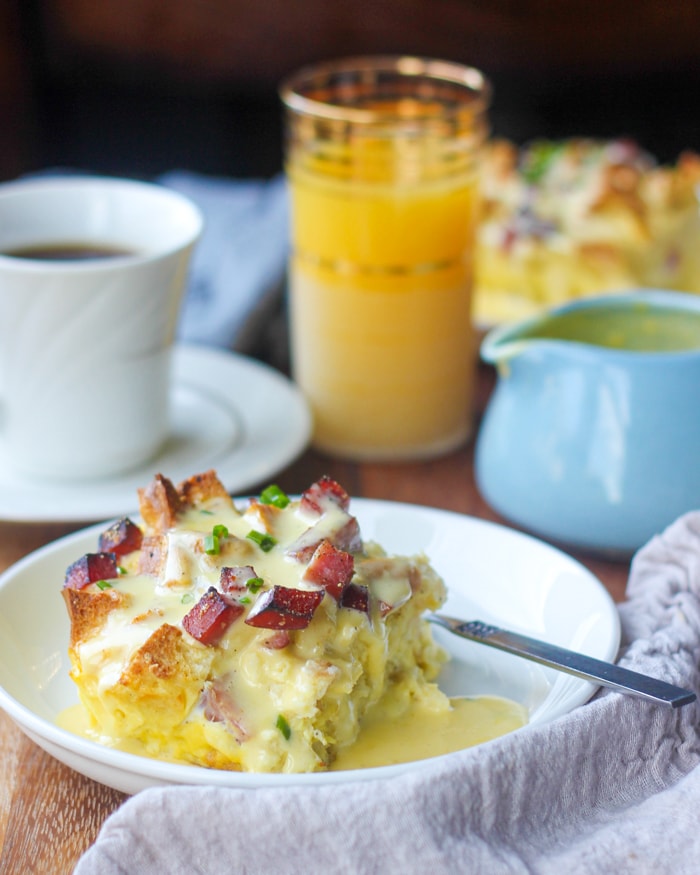 Plate of eggs benedict casserole with a cup of coffee and a glass of orange juice