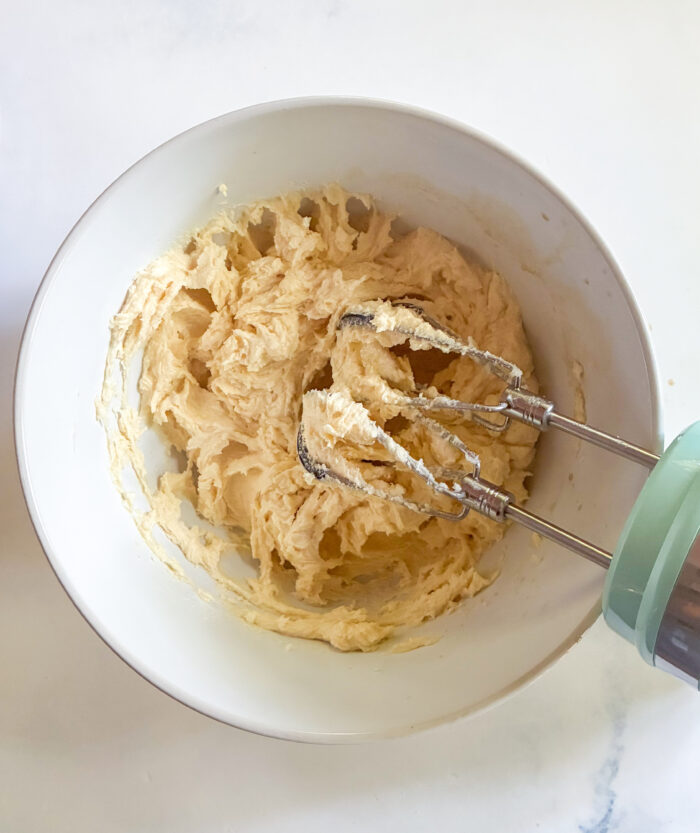 creamed butter and sugars in a bowl with hand mixer