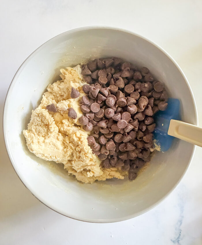 adding chocolate chips to cookie dough