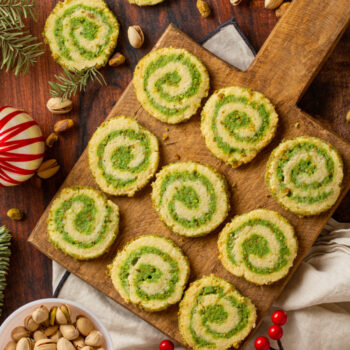 Pistachio pinwheel cookies on a wooden board ready for serving.