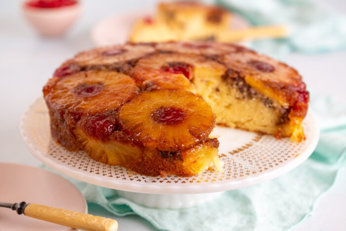 Pineapple Upside Down Cake with Pecans on a cake stand with a slice taken out