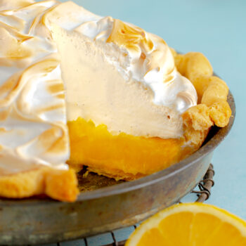 A whole lemon meringue pie with a slice taken out