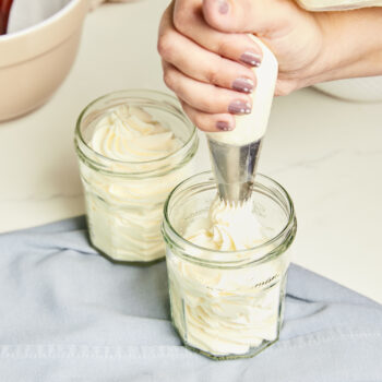Stabilized whipped cream being piped into a glass jar