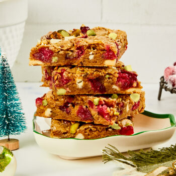 Cranberry white chocolate blondie squares stacked up on a Christmas plate