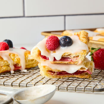 puff pastry pop tart cut in half with jam in the middle topped with glaze and fresh berries