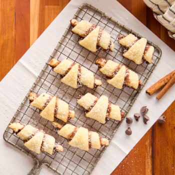 rugelach cookies sprinkled with powdered sugar on a cooling rack