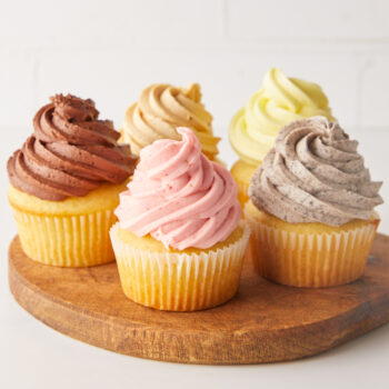 cupcakes with different toppings on a wooden plate
