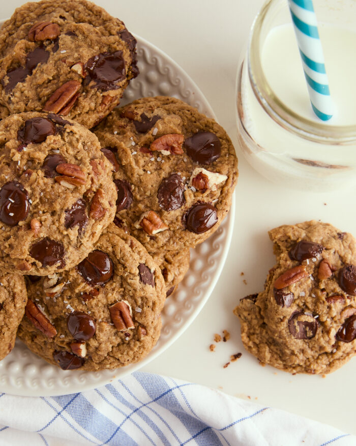 This is arguably the best ultimate chocolate chip cookies ever! The cookies are thick, and slightly crisp on the outside and incredibly chewy on the inside and made with brown butter and a good hit of flaky salt! brown butter chocolate chip cookies stacked on a plate with a bite taken out of one and a glass of milk