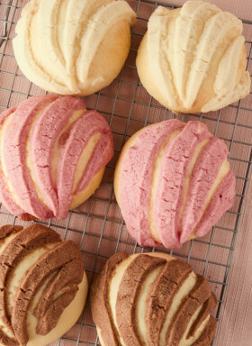 6 conchas in pink, white, and chocolate toppings on a cooling rack